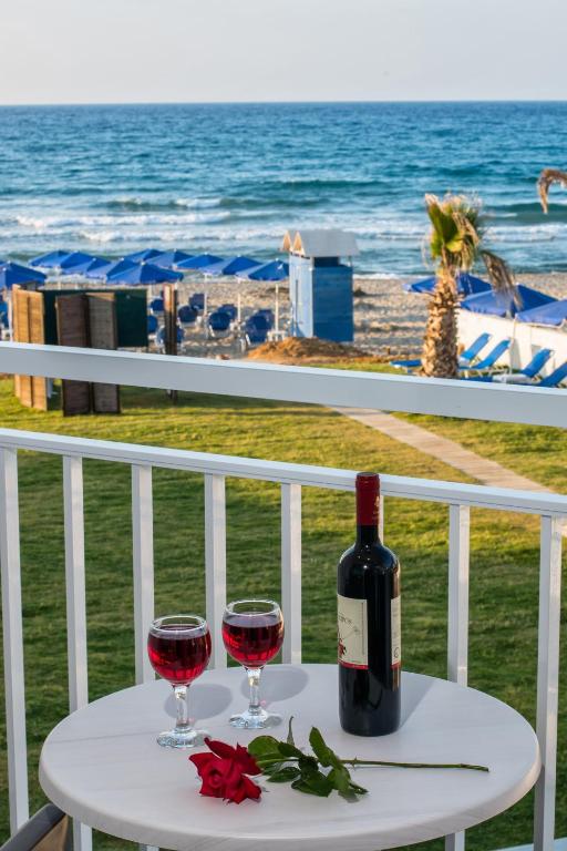 Romantiska aina ar divām glāzēm sarkanā vīna un pudeli uz galda, kas atrodas uz balkona ar skatu uz pludmali un jūru.