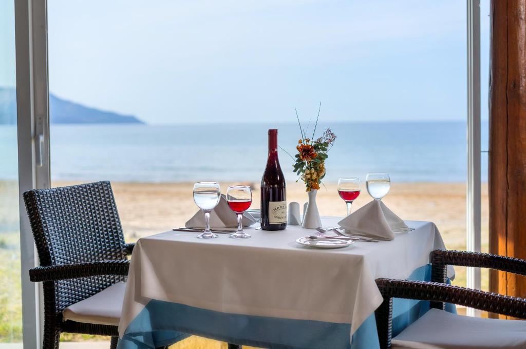 Romantisks restorāna galdiņš ar vīnu, dzērieniem un ziediem, skatoties uz jūras ainavu. Ideāli piemērots romantiskām vakariņām.