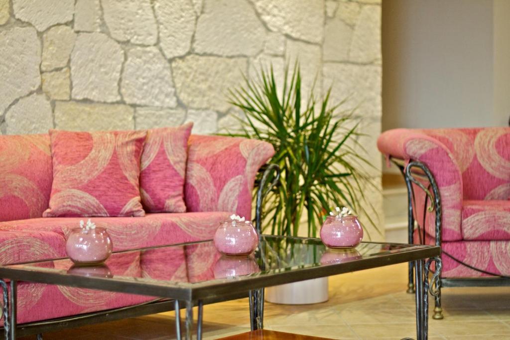 Mūsdienīgs viesistabas interjers ar rozā dīvāniem un stikla galdu, papildināts ar dekoratīviem podiņiem un telpaugiem. Ideāla atpūtas zona ar elegantu atmosfēru.
