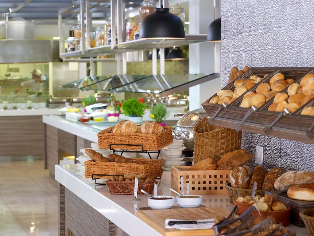 Brokastis ar svaigiem maizes izstrādājumiem un dažādiem garnējumiem, izkārtoti pie elegantas bufetes. Izsmalcināts interjers un gaļas pagatavošanas zona fona plānojuma.