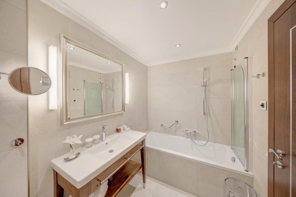 Mūsdienīgs vannas istabas dizains ar vannu, dušu un elegantu spoguli, kas papildina telpas estētiku. Interjers ir gaišs un funkcionāls, radot relaksējošu atmosfēru.