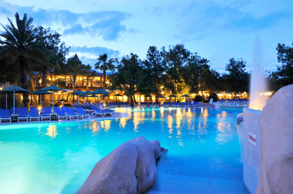 Marti Myra Hotel baseins ar palmām un nakts apgaismojumu