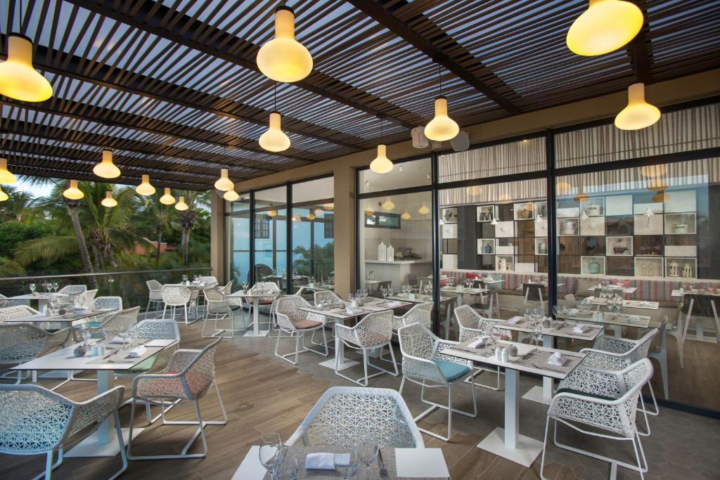 Moderns restorāns ar stilīgām galdiem un krēsliem, izgaismots ar dzeltenām lampām, ar skatu uz dabu. Terase ir plaša un aicinoša, ideāla maltītēm svaigā gaisā.