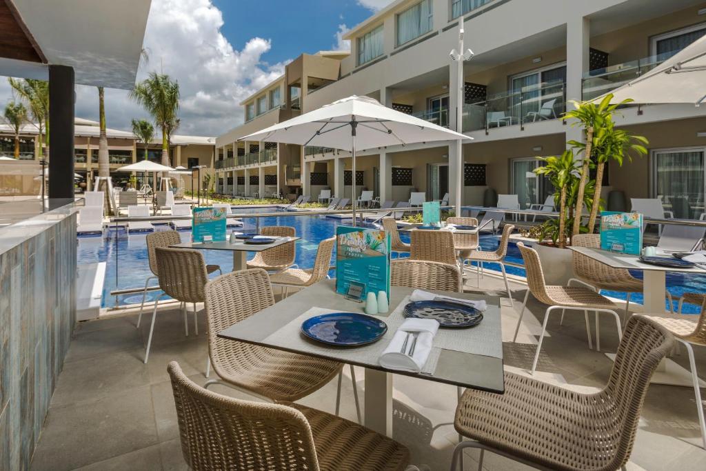 Peldbaseina zona ar ēdamgaldiem, saules aizsargiem un viesnīcas ēku fons. Ideāla vieta relaksācijai un atpūtai.