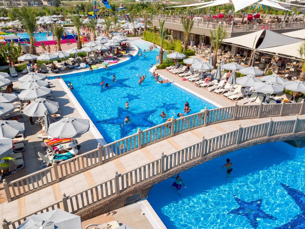 Royal Seginus viesnīcas peldbaseins ar tiltu un viesiem, kas atpūšas.