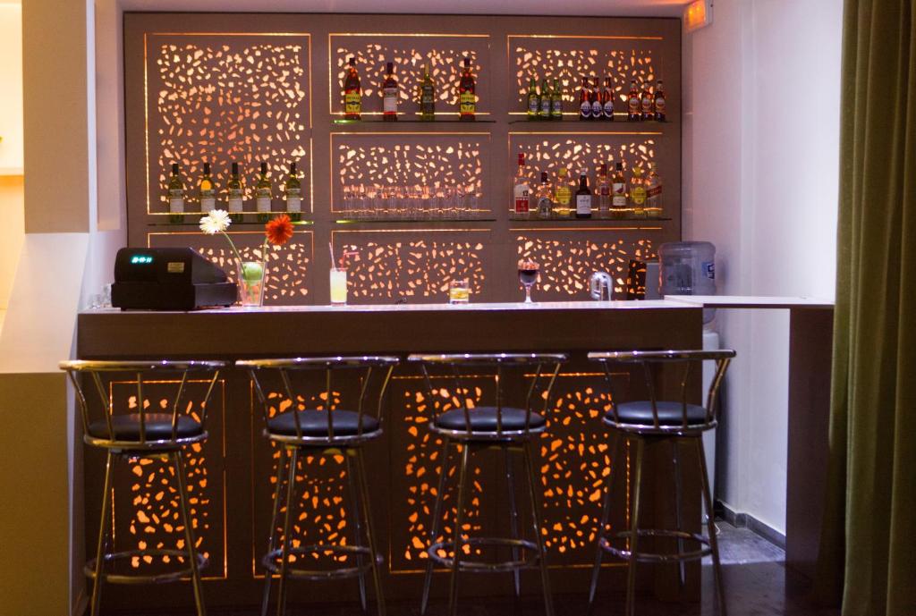 Mūsdienīgs bārs ar stilīgu apgaismojumu un dažādām alkohola pudelēm uz plauktiem. Bāra letē ir sēdvietas ar metāla krēsliem un dekoratīvām ziedu kompozīcijām.