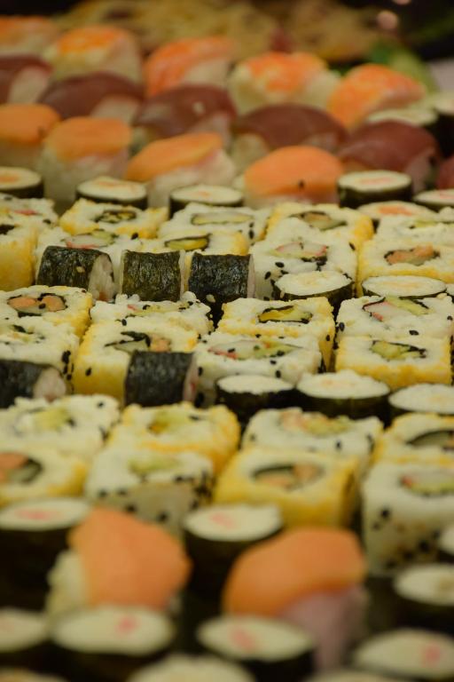 Svaigu sushi šķirņu kolekcija, tostarp dažādi rullīši un nigiri, izkārtoti krāsainās rindās.