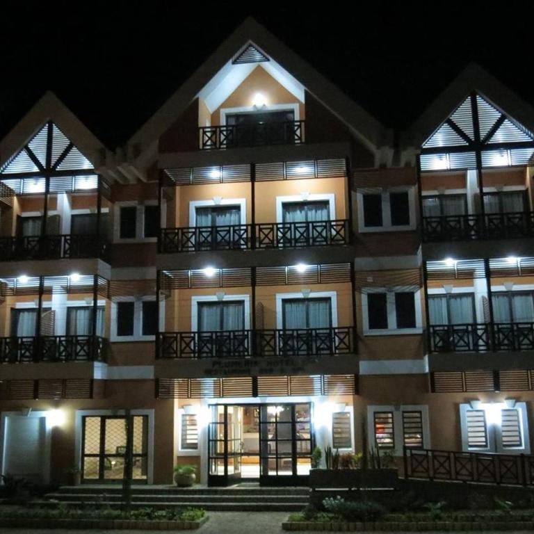 Hotel Plumeria fasāde naktī ar apgaismojumu.