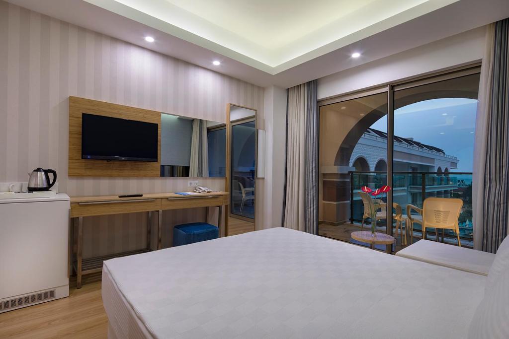 Moderns numurs Dosinia Luxury Resort ar balkonu un televizoru.