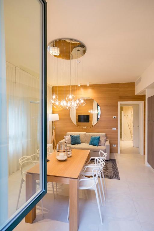 Mūsdienīgs viesistabas un ēdamistabas interjers ar koka akcentiem, elegantu apgaismojumu un mīkstām mēbelēm, radot siltu un viesmīlīgu atmosfēru.