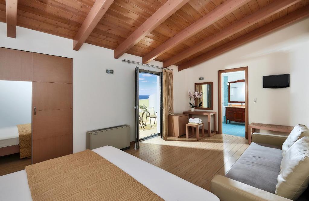 Mūsdienīga viesnīcas numura iekārtojums ar koka griestiem, divguļamo gultu, dīvānu un piekļuvi balkona zonai, no kuras paveras skats uz jūru. Numurā ir arī galds un spogulis.