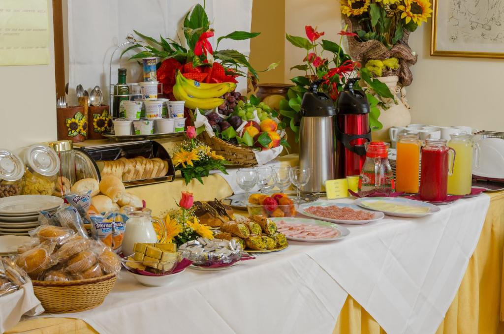 Bagātīgs brokastu galds ar dažādām delikatesēm, tostarp augļiem, maizi, konditorejas izstrādājumiem un dzērieniem. Ideāli piemērots viesnīcām vai brokastu pasākumiem.