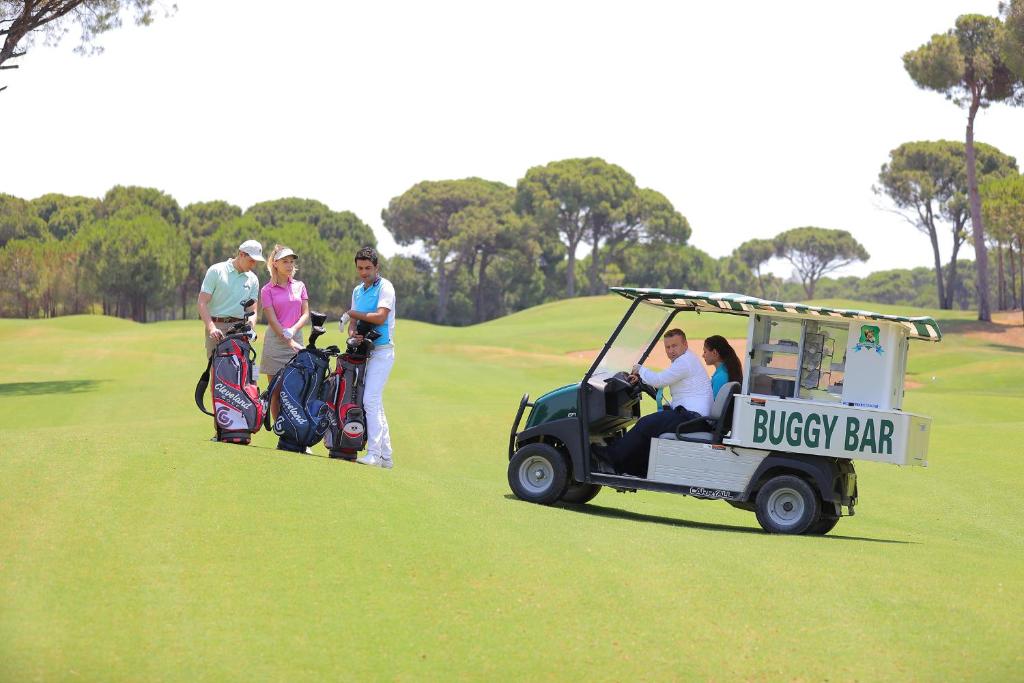 Golfa spēlētāji ar somām pie Sueno Hotels Golf Belek golfa laukuma