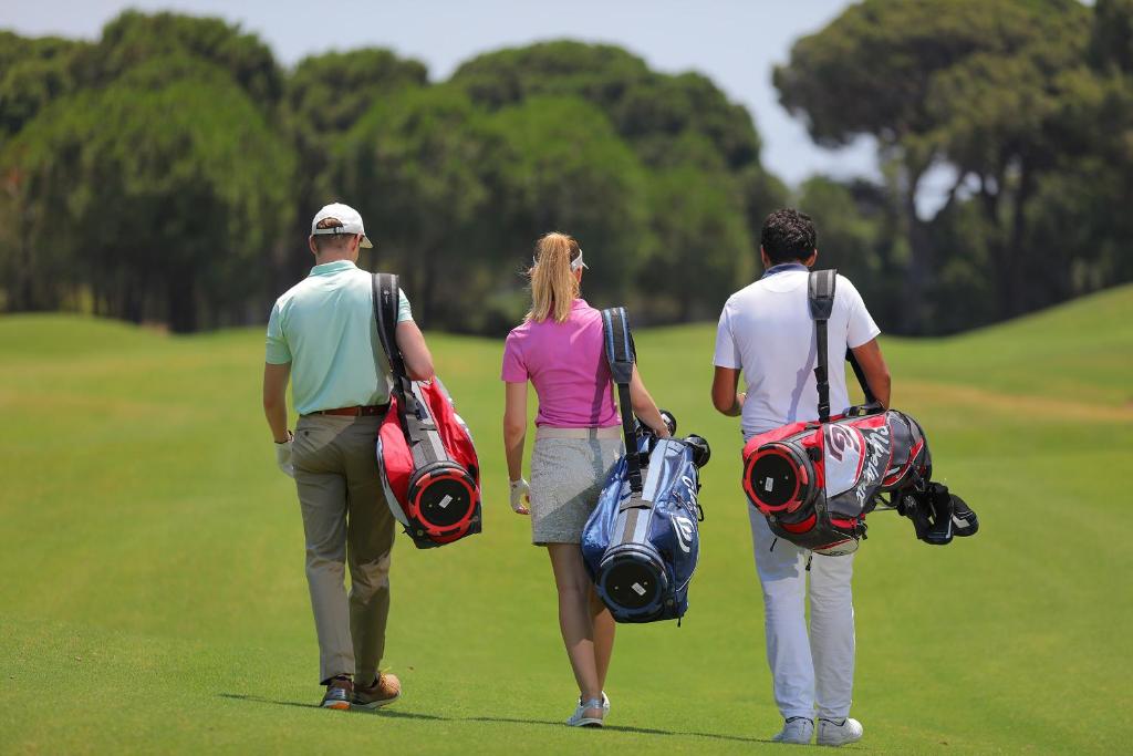 Trīs golfa spēlētāji, dodoties laukumā Sueno Hotels Golf Belek.