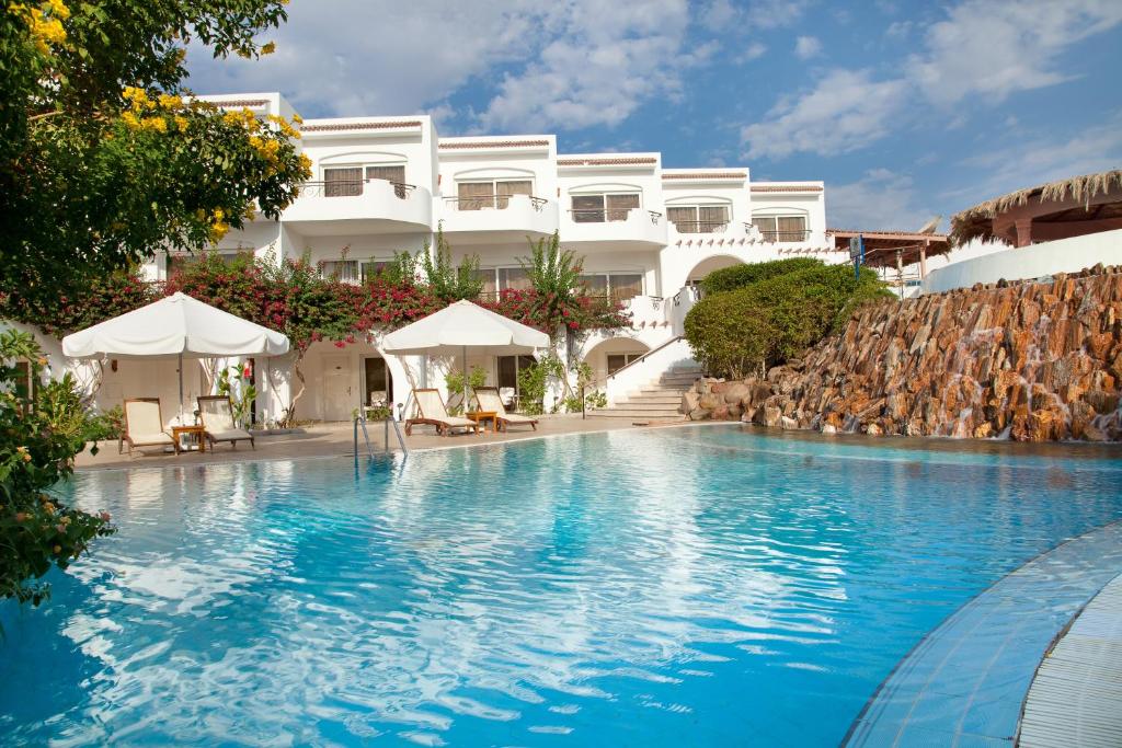 Iberotel Palace baseins ar saulessargiem un viesnīcas ēka piekrastē