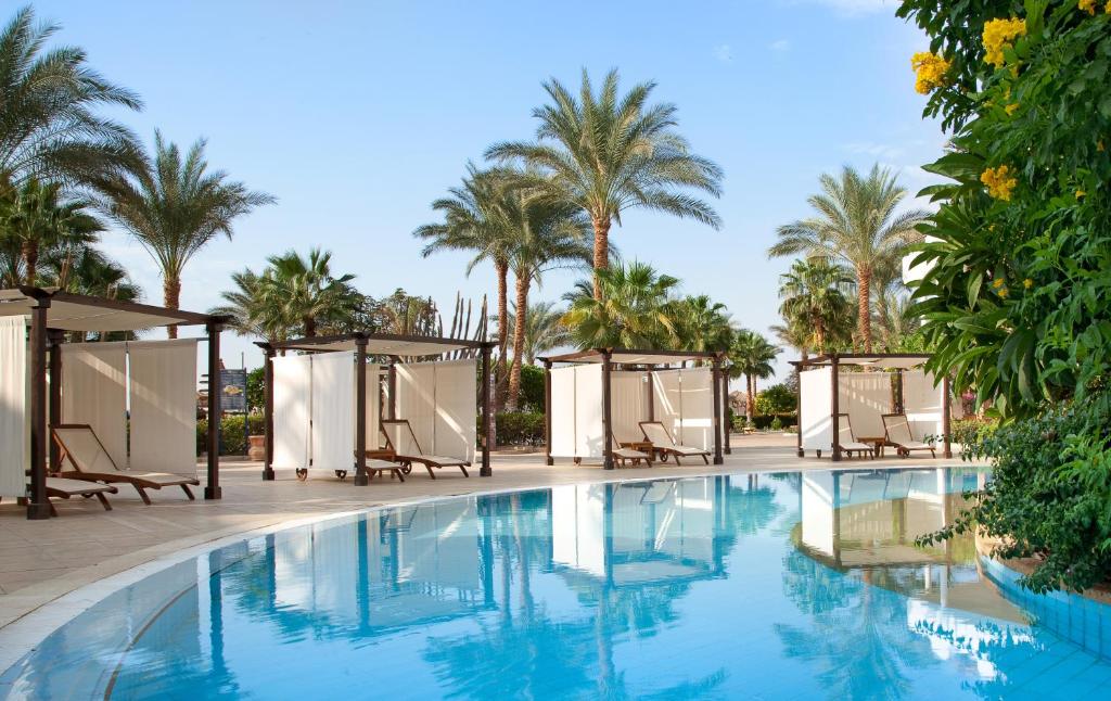 Iberotel Palace baseins ar palmām un saulessarga vietām