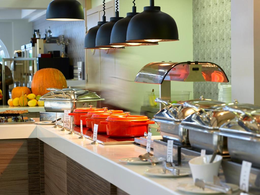 Bufetes galda ar dažādiem ēdieniem un izsmalcinātu apgaismojumu, kas rada patīkamu atmosfēru. Sarkanās un sudraba trauki piepildīti ar gardumiem, papildināti ar dārzeņiem.