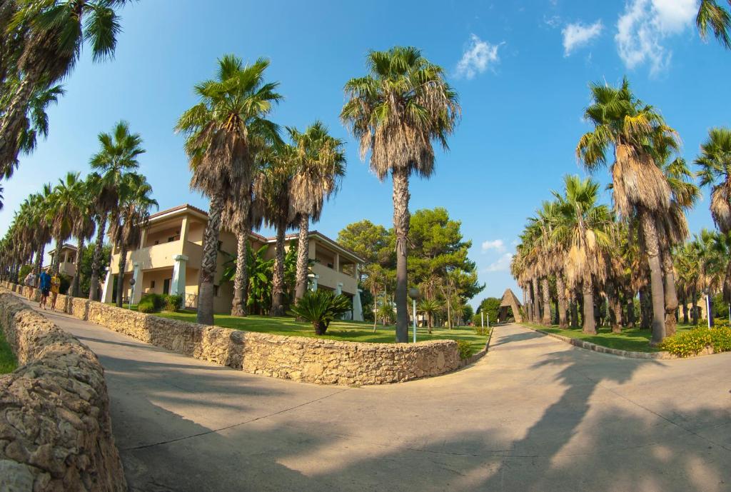 Tropiska ainava ar palmām un modernām ēkām, kas veido mierīgu un relaksējošu atmosfēru. Ideāla vieta atpūtai un brīvdienām.