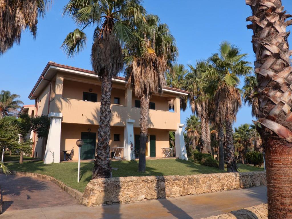 Mājas komplekss ar palmām un saulainu debesi, kas piedāvā relaksējošu atmosfēru. Ideāla vieta atpūtai pie dabas.