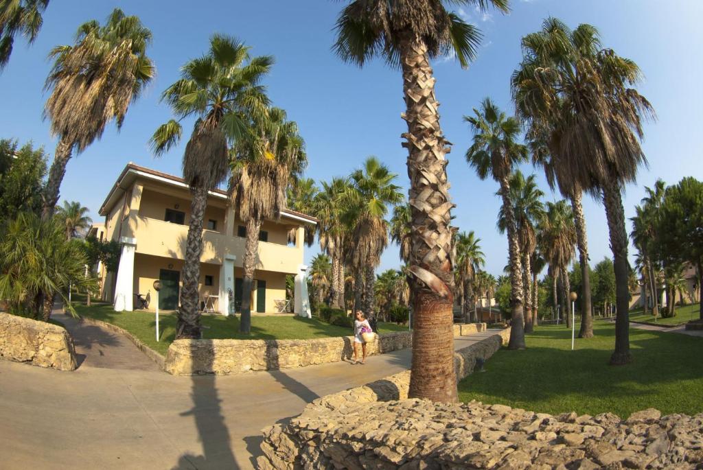 Tropiska ainava ar palmām un mājām, kas izvietotas gleznainā parkā. Ideāla vieta relaksācijai un atpūtai.