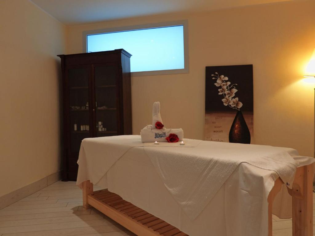 Mierīgas un relaksējošas masāžas telpas interjers ar masāžas galdu, dekorētu ar rozēm un sveču gaismu. Uz sienas redzams mākslas darbs ar ziediem, radot patīkamu atmosfēru.