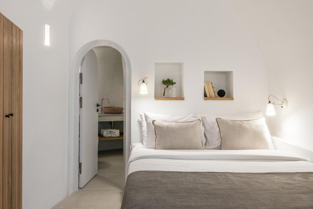 Mūsdienīga guļamistaba ar baltām sienām un ērtu gultu, kurā ir dekoratīvi spilveni un minimālistiski elementi. Telpā ir neliels vannasistabas stūris ar mūsdienīgu izskatu.