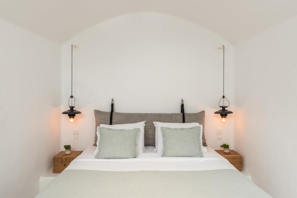 Mūsdienīgs guļamistabas interjers ar gaismas ķermeņiem, kas piekārtoti abās gultas pusēs, un neitrālām krāsām, kas rada mierīgu atmosfēru. Gultas galva ir izveidota no pelēka auduma, papildināta ar zaļām spilveniem un koka naktsgaldiņu.