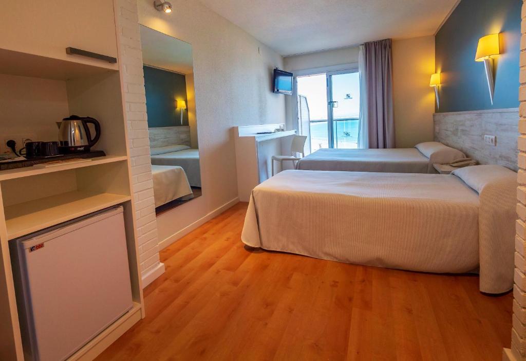 Mūsdienīgs viesnīcas numurs ar divām atsevišķām gultām, mini virtuvi un skatu uz jūru. Telpa ir gaiša un ērta, ar modernām mēbelēm un lielu logu.