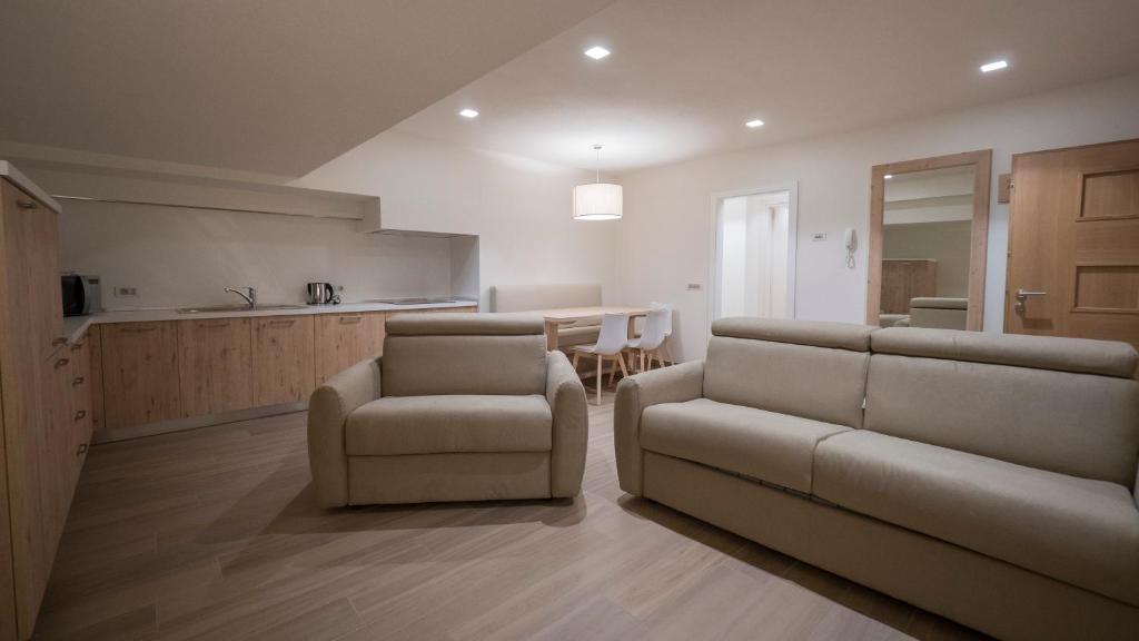 Mūsdienīgs viesistabas interjers ar ērtām dīvānām, virtuvi un ēdamzonu, kas izstrādāta gaišās krāsās. Telpa ir plaša un labi apgaismota.