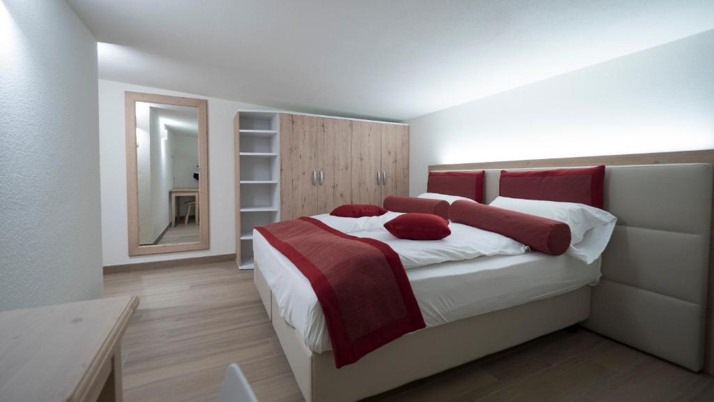 Mūsdienīga guļamistaba ar ērtu gultu un sarkanām akcentu spilveniem, papildināta ar spoguli un plauktu. Gaismas dizains rada patīkamu atmosfēru.
