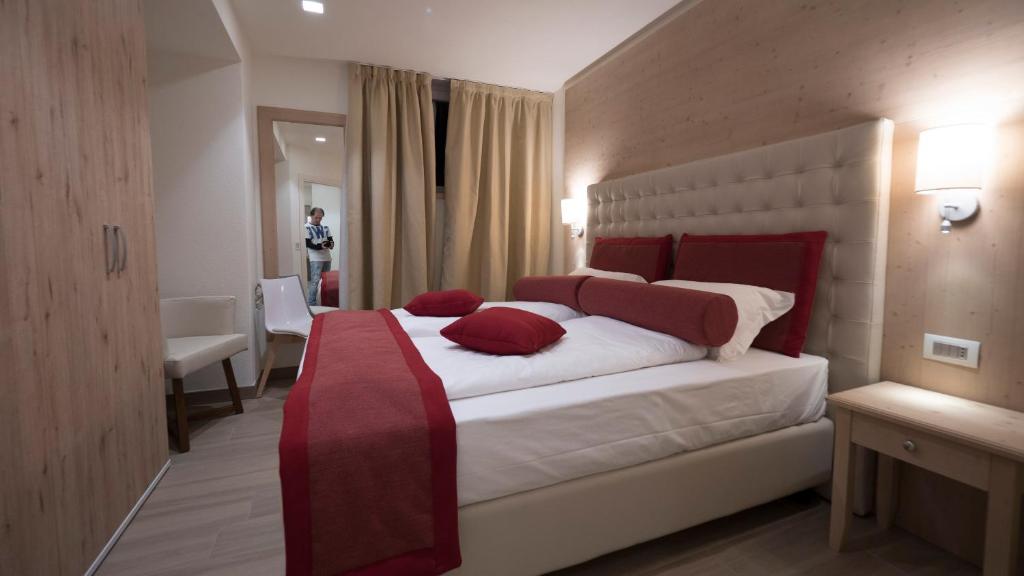 Mūsdienīga guļamistaba ar divguļamo gultu un sarkanām akcentu spilveniem, apkārtējo interjeru veido neitrālas krāsas un koka elementi. Guļamistabā ir ērta krēsla un spoguļa zona.