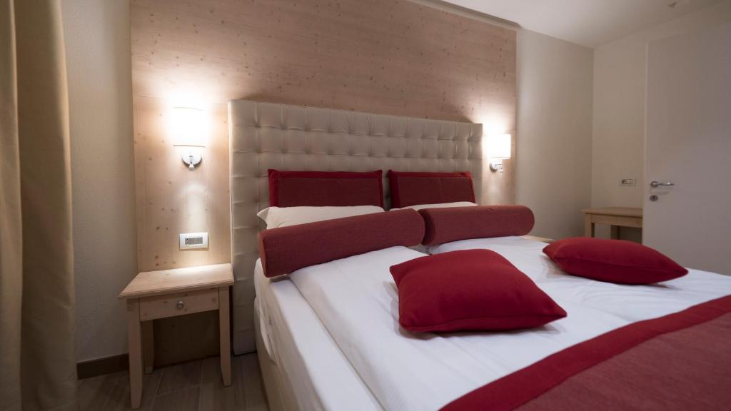 Mūsdienīgs guļamistabas interjers ar gultu, dekoratīvajām spilveniem un siltu apgaismojumu. Sienas apdare no koka un koka naktsgaldiņš papildina telpas stilu.