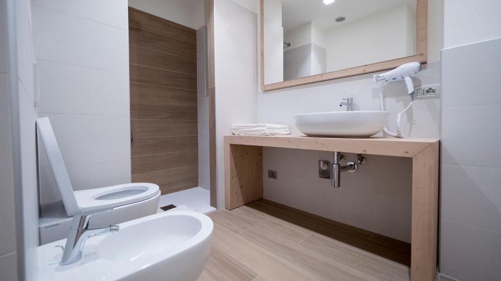 Mūsdienīga vannas istaba ar koka detaļām, baltu izlietni un divām sanitārām ierīcēm. Gaisma un telpas izvietojums rada patīkamu atmosfēru.