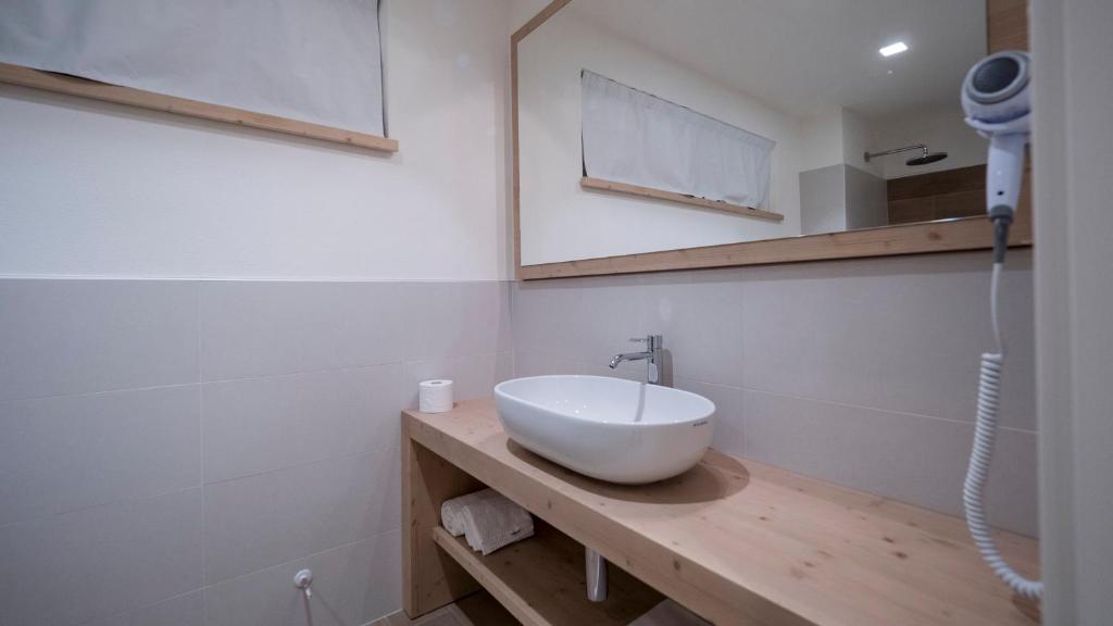 Moderns vannas istabas dizains ar gaišu koka izstrādājumu un elegantu izlietni. Telpa ir gaiša un gaumīga, piedāvājot komfortu un estētiku.