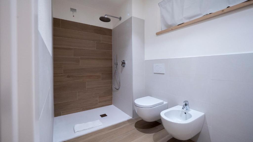 Mūsdienīga vannas istaba ar dušas kabīni, koka izskata flīzēm un baltām sanitārajām iekārtām. Telpa ir gaiša un eleganta, piedāvājot patīkamu atpūtas vidi.