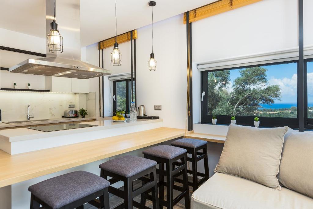 Mūsdienīga virtuve ar atvērtu plānojumu, kas piedāvā skatu uz jūru, gaišas krāsas interjers un ērtas sēdvietas pie galda.