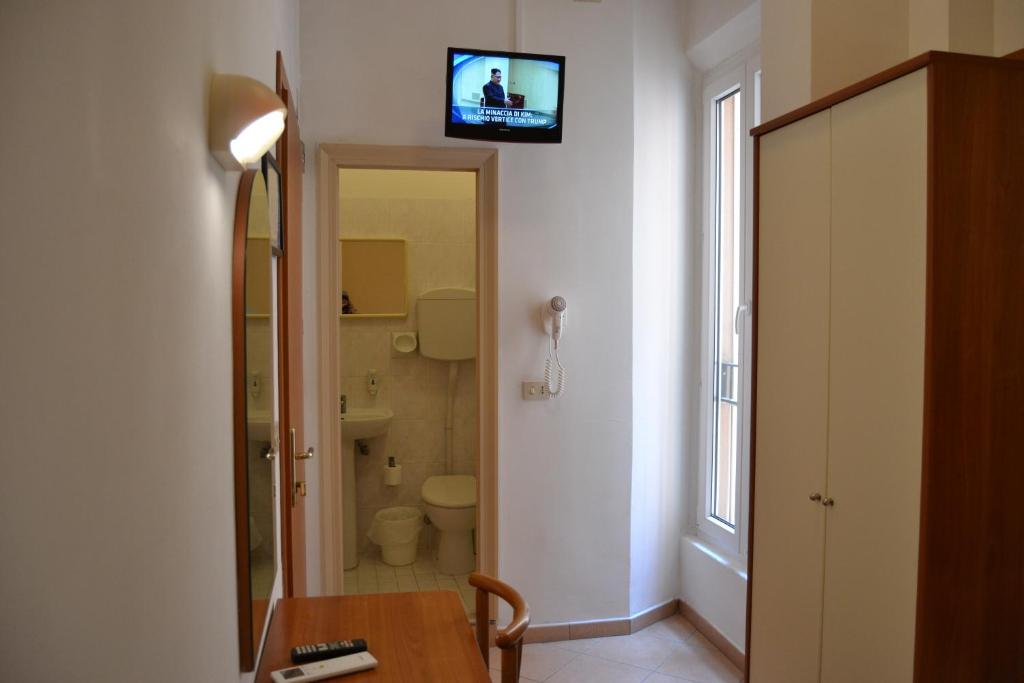 Mūsdienīga istaba ar televizoru, galdu un krēslu, kas ved uz vannas istabu. Gaismas un logi nodrošina labu apgaismojumu.