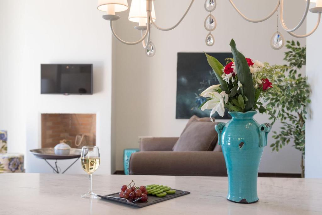 Skaista viesistaba ar ziedu podu, vīna glāzi un uzkodu šķīvi, radot relaksējošu atmosfēru. Fons ar televizoru un dīvānu papildina interjera eleganci.