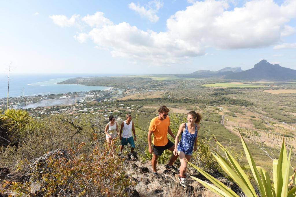 Grupa cilvēku kāpj kalnā ar skatu uz piekrasti pie Veranda Tamarin Hotel & Spa.