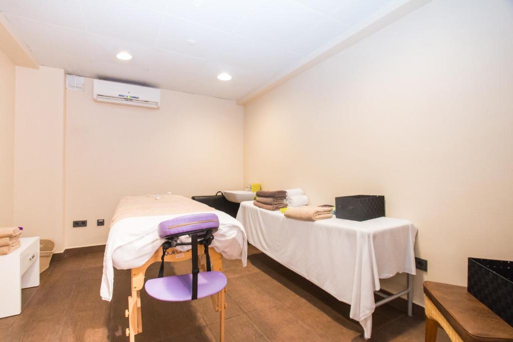 Masāžas telpa ar divām masāžas galdiem, svaigiem dvieļiem un relaksējošu atmosfēru. Telpas dizains ir vienkāršs un mūsdienīgs, nodrošinot komfortu un mieru.