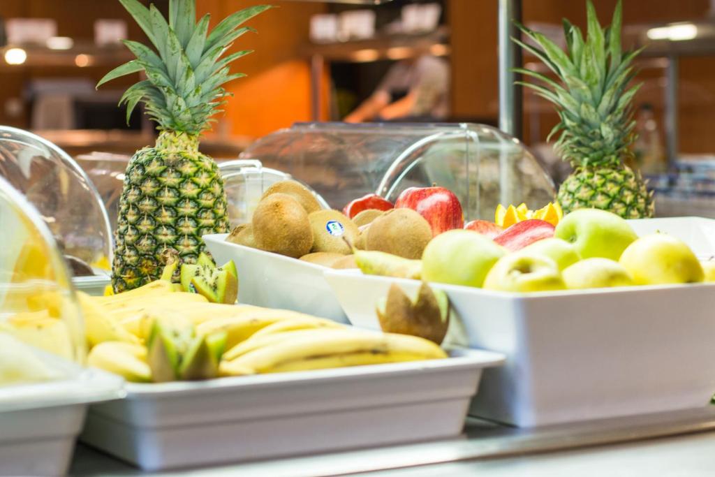 Dažādu augļu bufete ar ananāsiem, banāniem, āboliem un kivi. Krāsaini un svaigi augļi uz galda, kas piedāvā veselīgas uzkodas.
