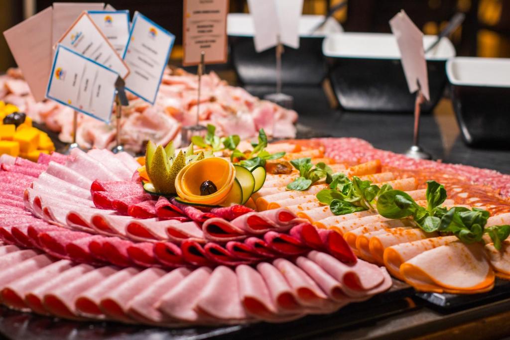 Svaigu gaļas un dārzeņu uzkodu plāksne ar krāsainām šķēlītēm un augļiem, dekorēta ar zaļumiem. Ideāla izvēle svinībām vai svētkiem.