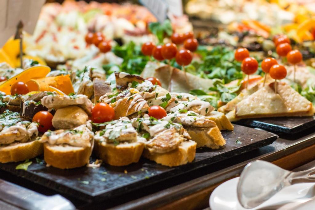 Svaigi sagatavoti uzkodu šķīvji ar maizi, tomātiem un zaļumiem, kas tiek pasniegti bufetē. Ideāli piemēroti svinībām un svētkiem.