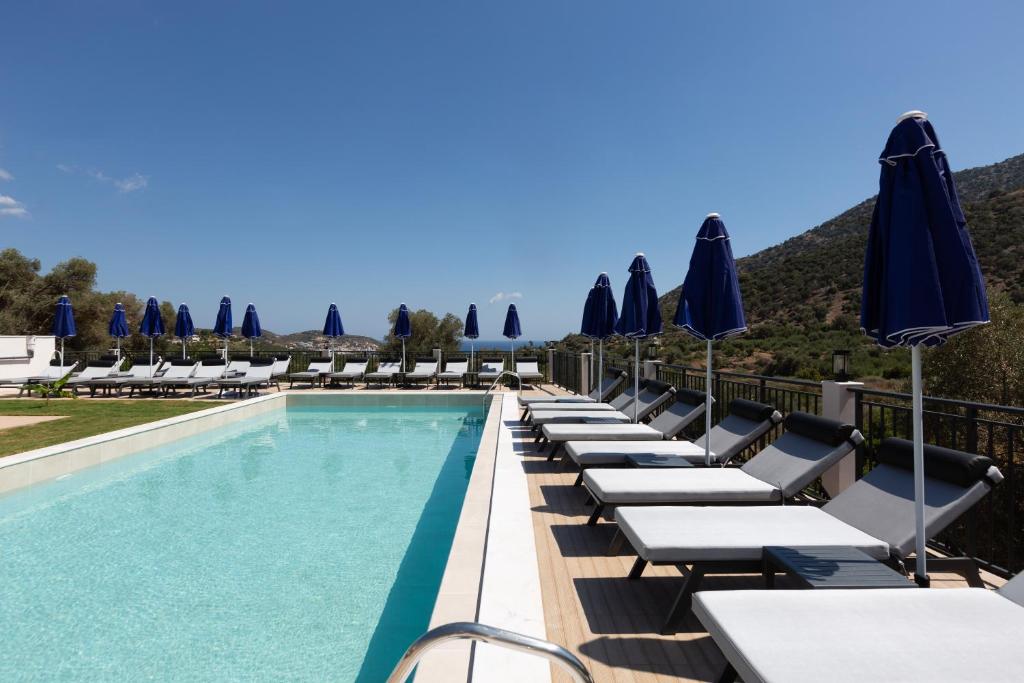 Baseins ar guļamkrēsliem un saules lietussargiem, kas izvietoti gar ūdens malu, ar kalnu ainavu fonā. Ideāli piemērots relaksācijai un atpūtai.