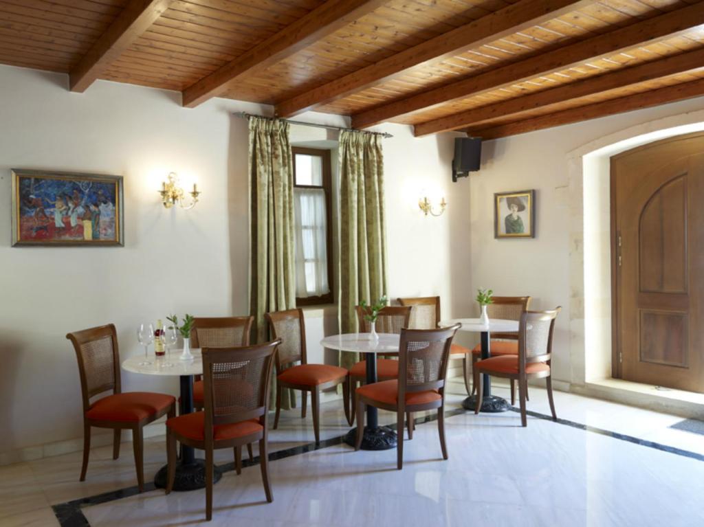 Elegants un gaumīgs restorāna interjers ar baltiem galdiem, koka griestiem un sarkaniem krēsliem. Uz sienas ir mākslas darbi, kas papildina atmosfēru.