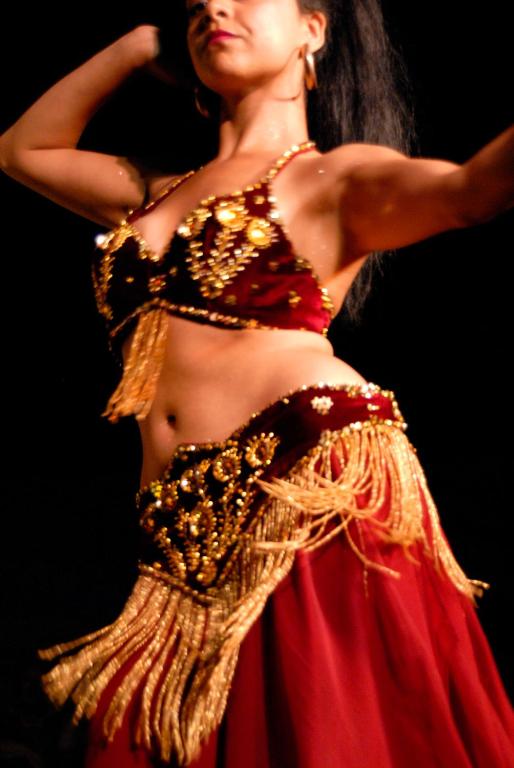 Sieviete dejo, tērpta sarkanā un zeltītā tērpā.