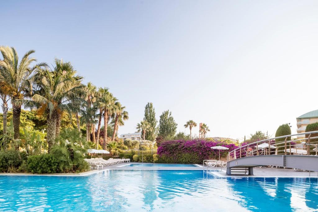 Vasaras peldbaseins ar palmām un ziedošiem krūmiem, kas rada relaksējošu un eksotisku atmosfēru. Ideāla vieta atpūtai un izklaidei.