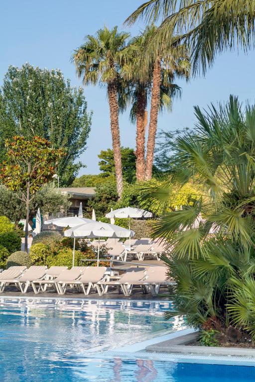 Peldbaseins ar saulessargiem un atpūtas krēsliem, ko ieskauj palmām un zaļa veģetācija. Ideāla vieta relaksācijai un atpūtai.