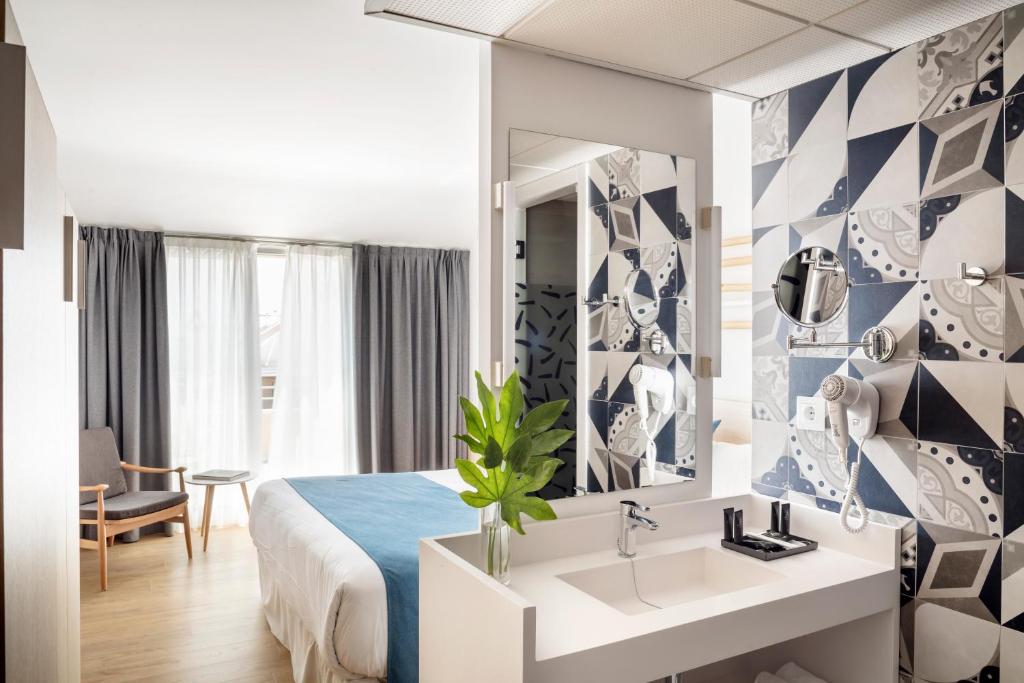 Mūsdienīgs viesnīcas numurs ar elegantu vannas istabu un dekoratīvām flīzēm. Telpā ir gultas, sēdvietas un lieli logi, kas nodrošina dabisko apgaismojumu.