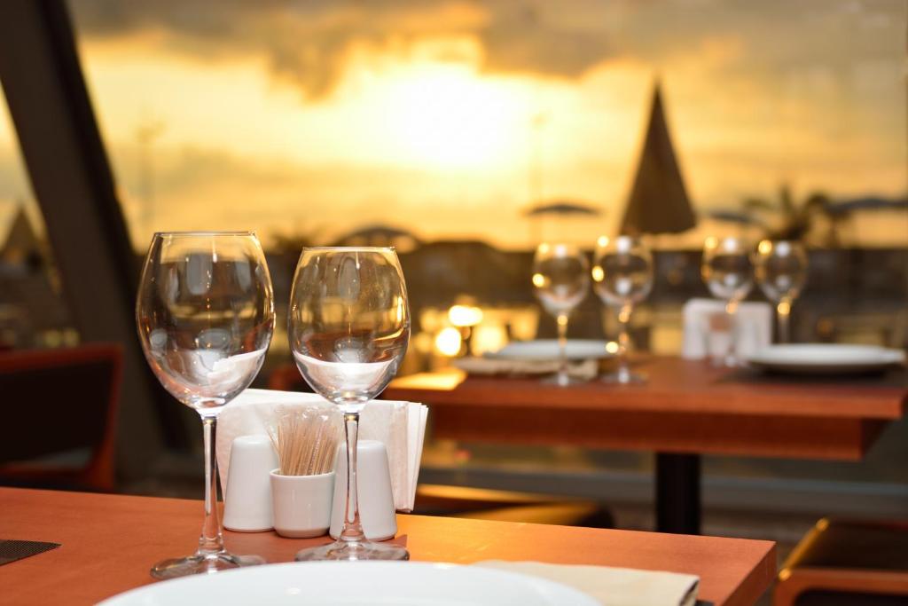 Romantiska vakariņas restorānā ar glāzēm un saulrietu fons. Ideāli piemērots romantiskām vai svinīgām reizēm.